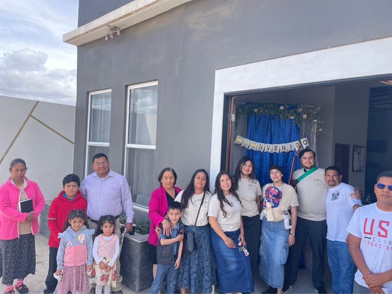 Miembros de la iglesia y niños en la entrada de la iglesia de Ensenada, con una guirnalda de bienvenida en la puerta.