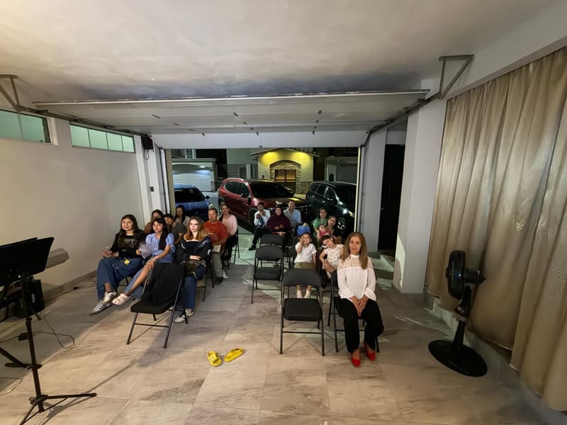 The Tijuana meeting room seen from the front, with people seated and the street visible through the open door.