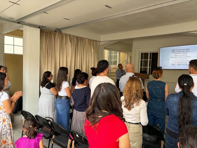 Miembros de la iglesia de Tijuana de pie durante un servicio de adoración, vistos de espaldas.